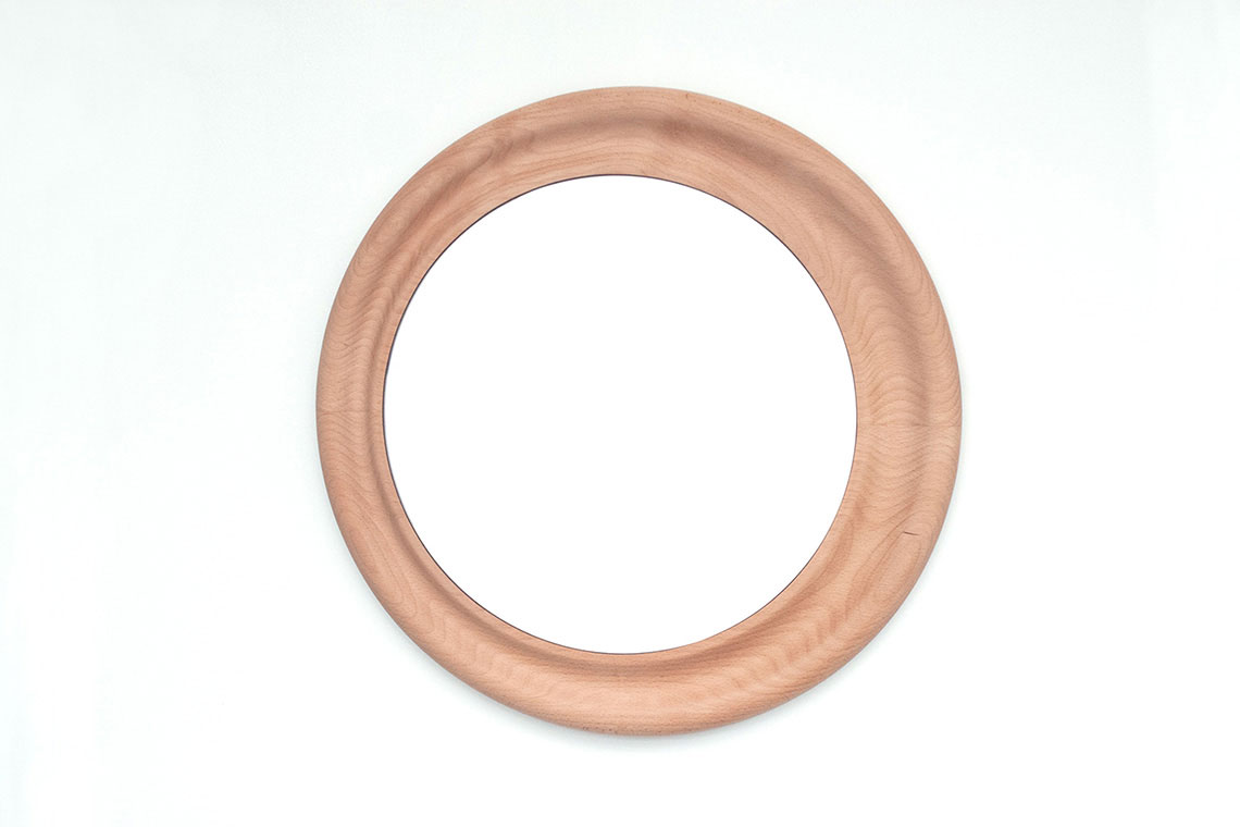 Crater Mirror encased in sculptural wood frame is a play with asymmetrically nested circles that enlighten the start of your day; shown in large size 50 cm in diameter.