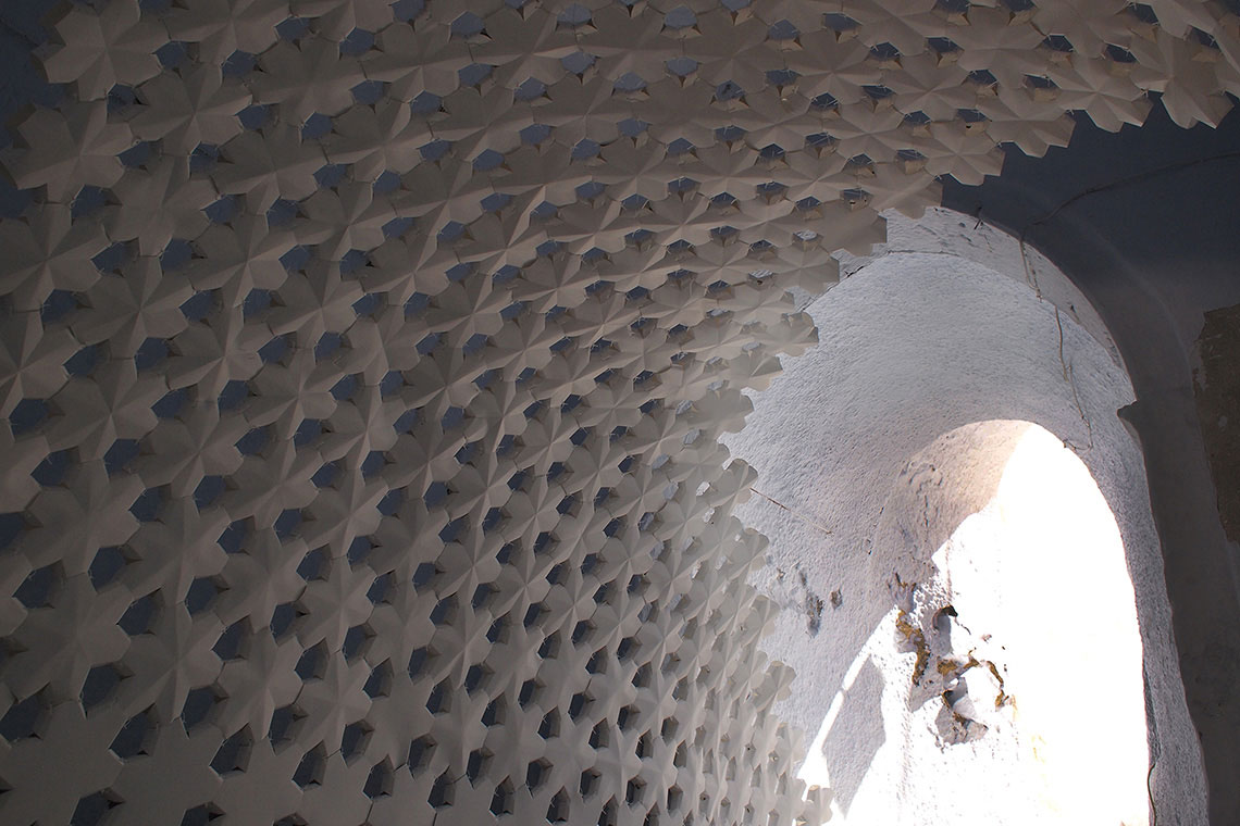 View of Daphne Installation completed by 24d-studio showing detailed view of sculptural white watercolor paper panels connected into an arch within a tunnel on Santorini Island.