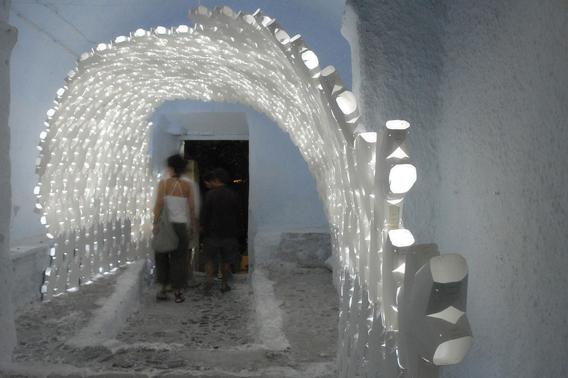 Photo showing Daphne installation paper panel arch assembly with lights on during night time situated within a tunnel in Pyrgos
