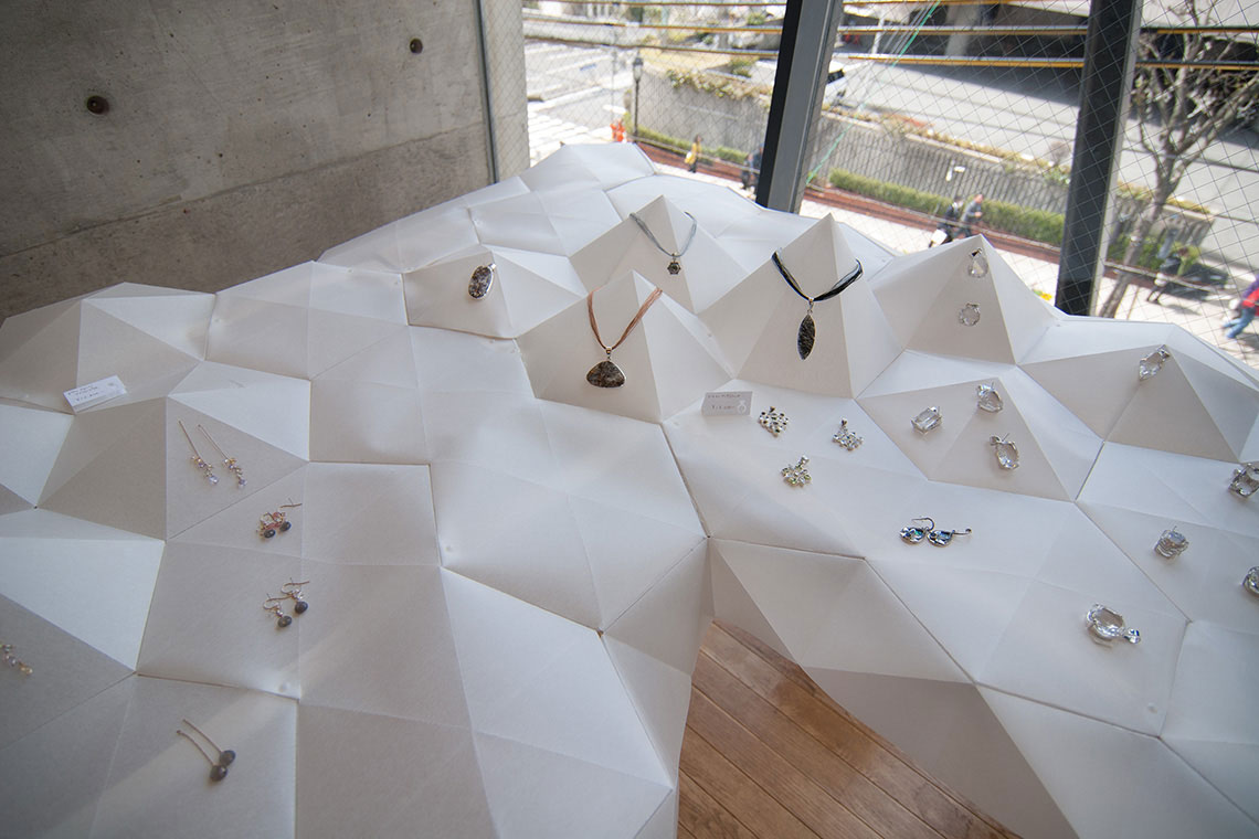 Rice paper hexagon tiles and pyramids were folded for necklace and bracelet display for Kan exhibition design by 24d-studio.